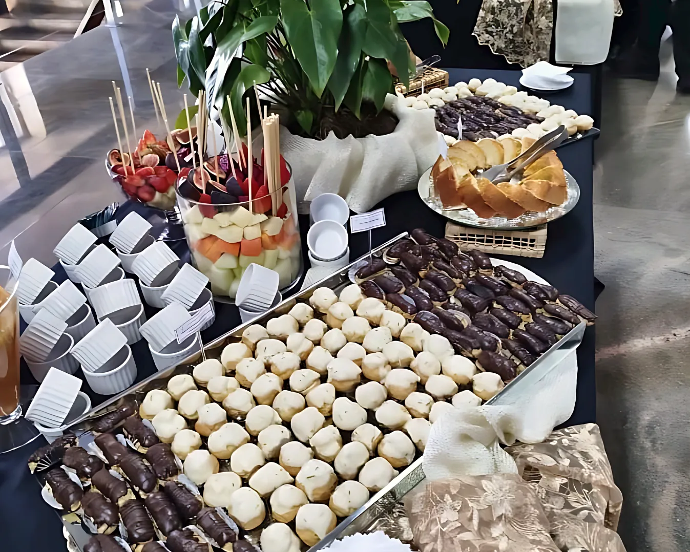 Mesa de coffee break corporativo com carolinas, doces e frutas